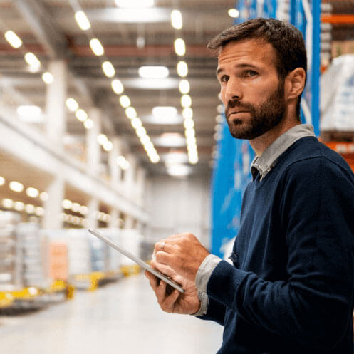 Symbolic image of a man holding a tablet and examining a logistics property